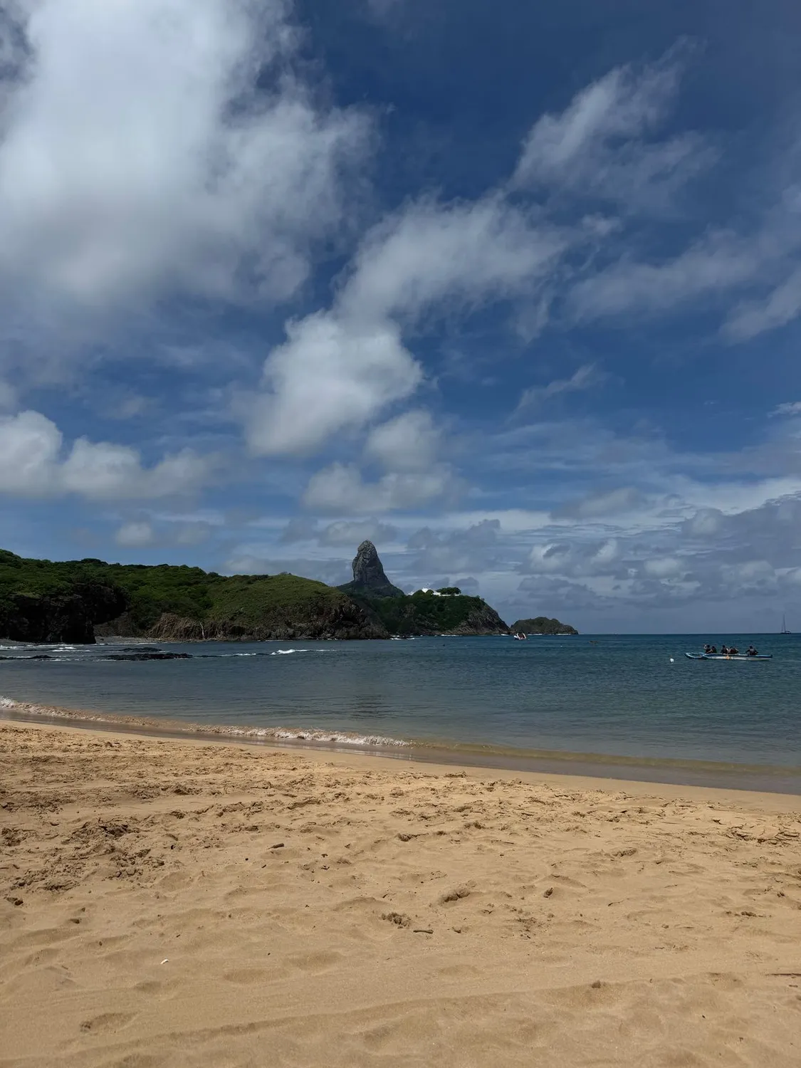 Praia de areia cercada por encostas verdes em Fernando de Noronha
