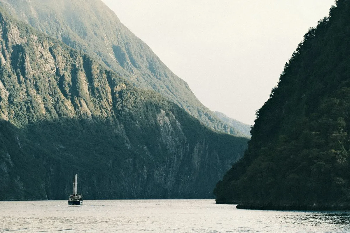Barco navegando entre penhascos no fiorde de Milford Sound