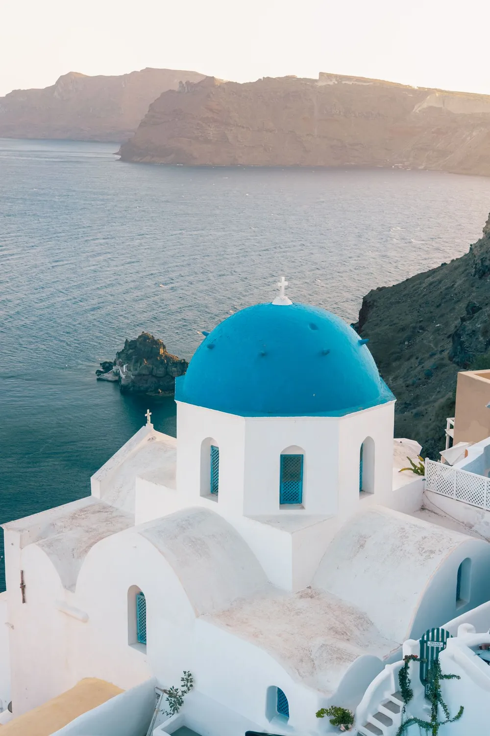 Igreja de domo azul com vista para o litoral de Santorini